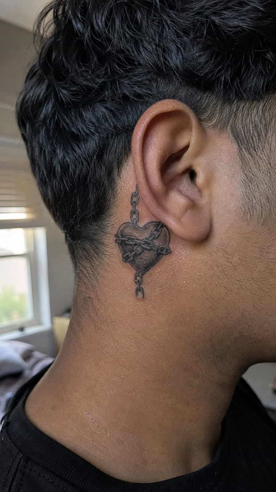 Healed heart in chains tattoo on a adult person's behind the ear, photographed in a natural casual close three-quarter view — study 3