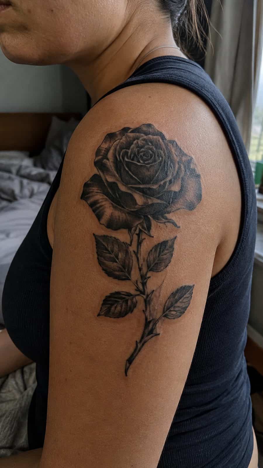 Healed black rose in bloom tattoo on a adult person's shoulder, photographed in a natural gentle side angle that clearly shows how the — study 2