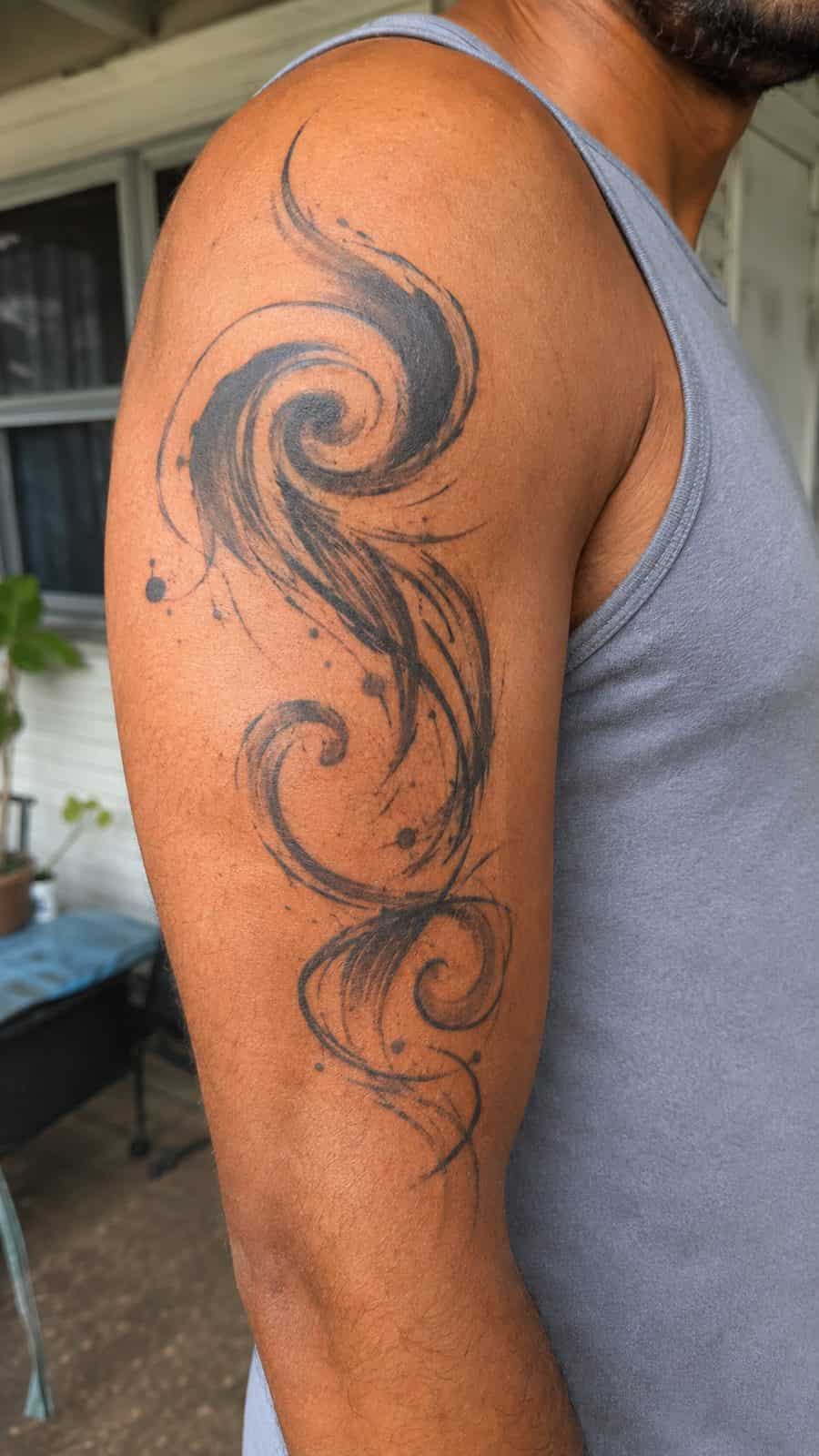 Healed abstract swirl designs tattoo on a adult person's outer upper arm, photographed in a natural casual close three-quarter view — study 1