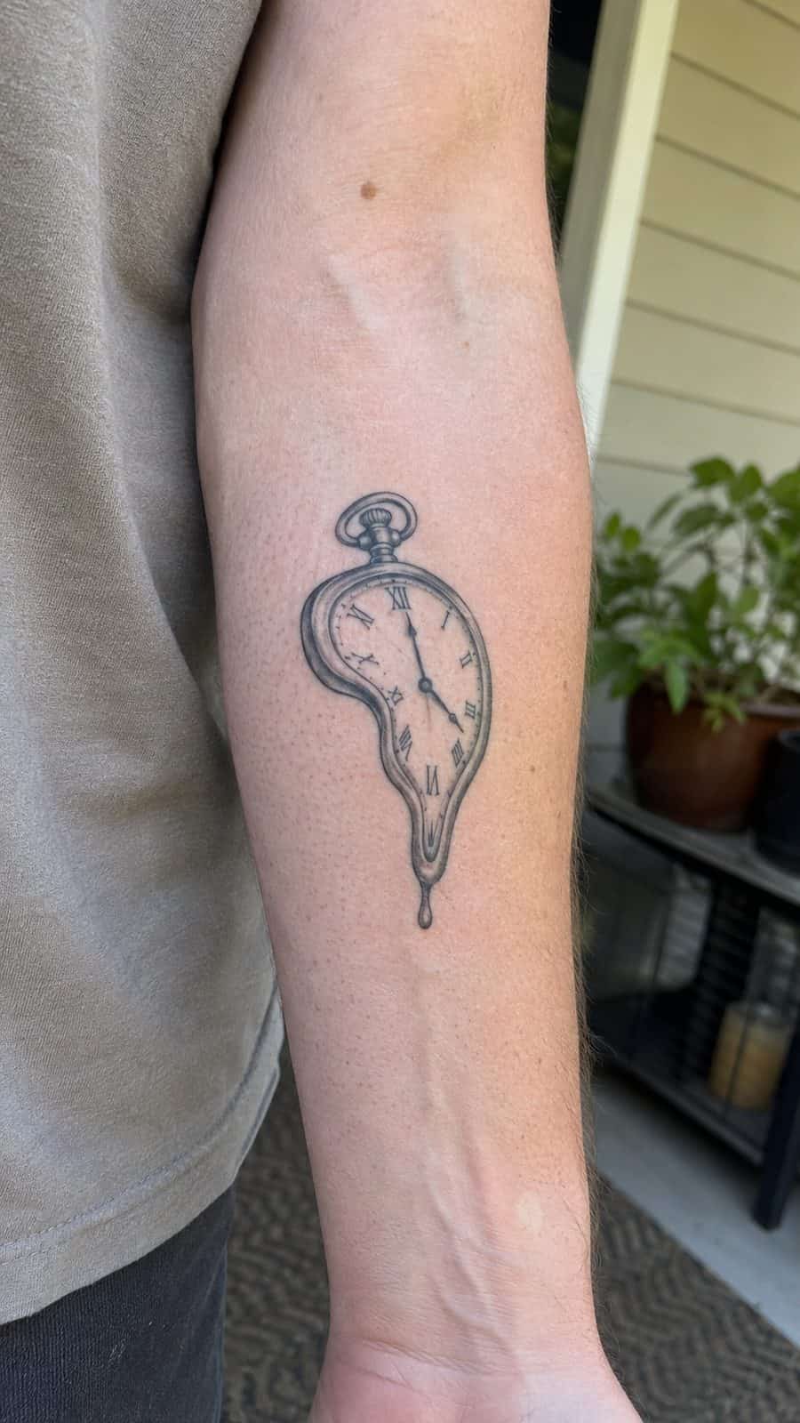 Healed melting clock tattoo on a adult person's inner forearm, photographed in a natural straight-on close view, a touch off-center — study 3