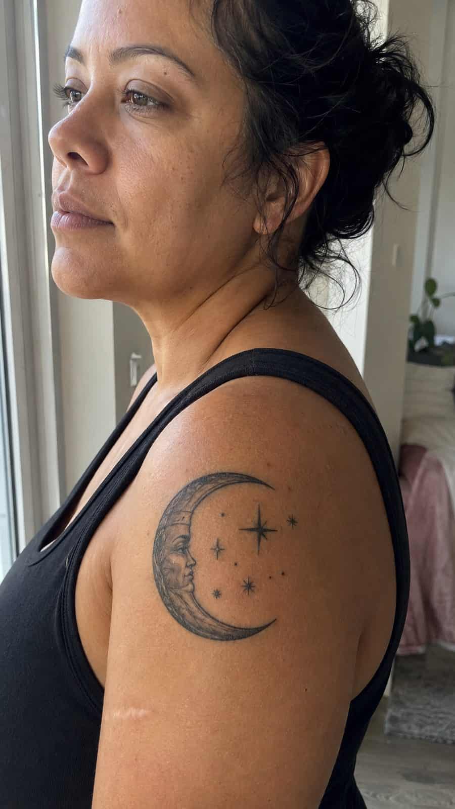 Healed crescent moon and stars tattoo on a adult person's shoulder, photographed in a natural waist-height candid close-up — study 3