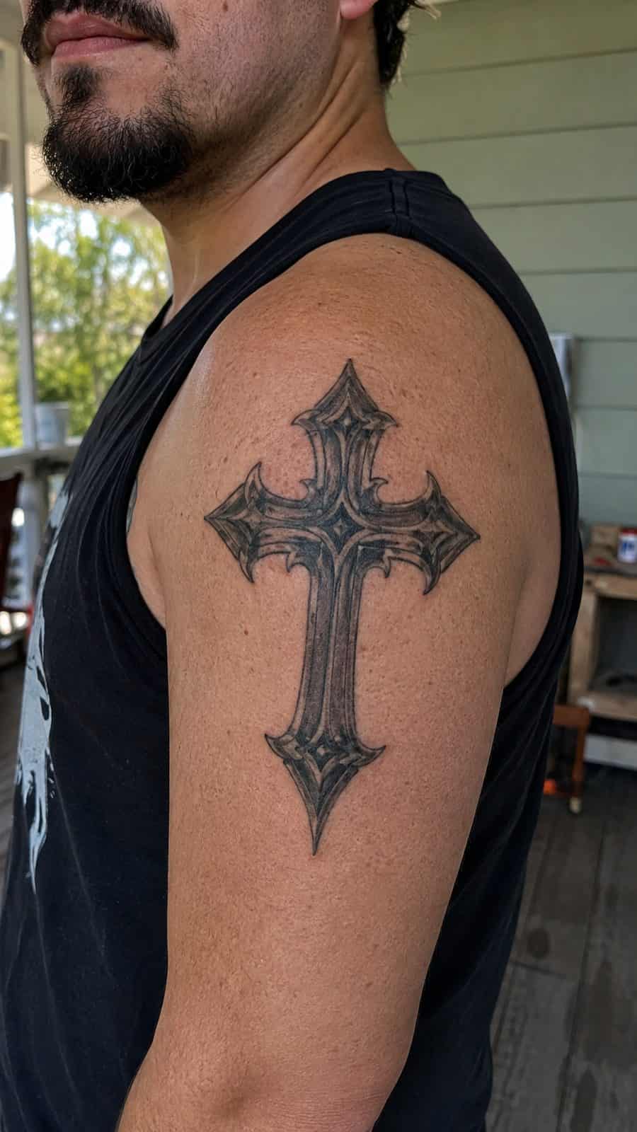 Healed gothic cross tattoo on a adult person's shoulder, photographed in a natural casual close three-quarter view — study 1