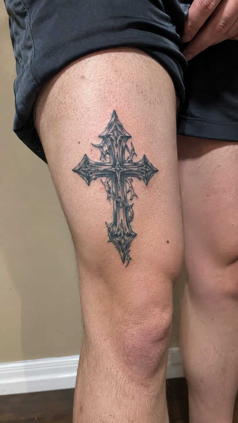 Healed gothic cross tattoo on a adult person's outer thigh, photographed in a natural straight-on close view, a touch off-center like — study 2