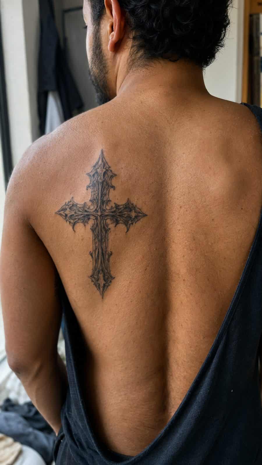 Healed gothic cross tattoo on a adult person's upper back, photographed in a natural gentle side angle that clearly shows how the ink — study 3