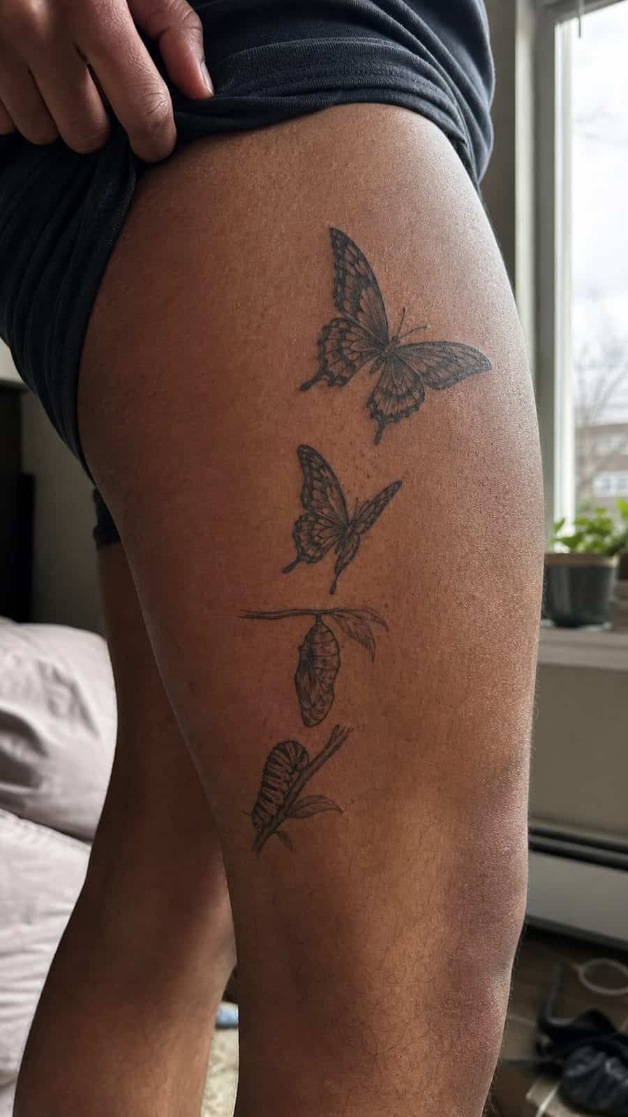 Healed butterfly in transition tattoo on a adult person's outer thigh, photographed in a natural casual close three-quarter view — study 1