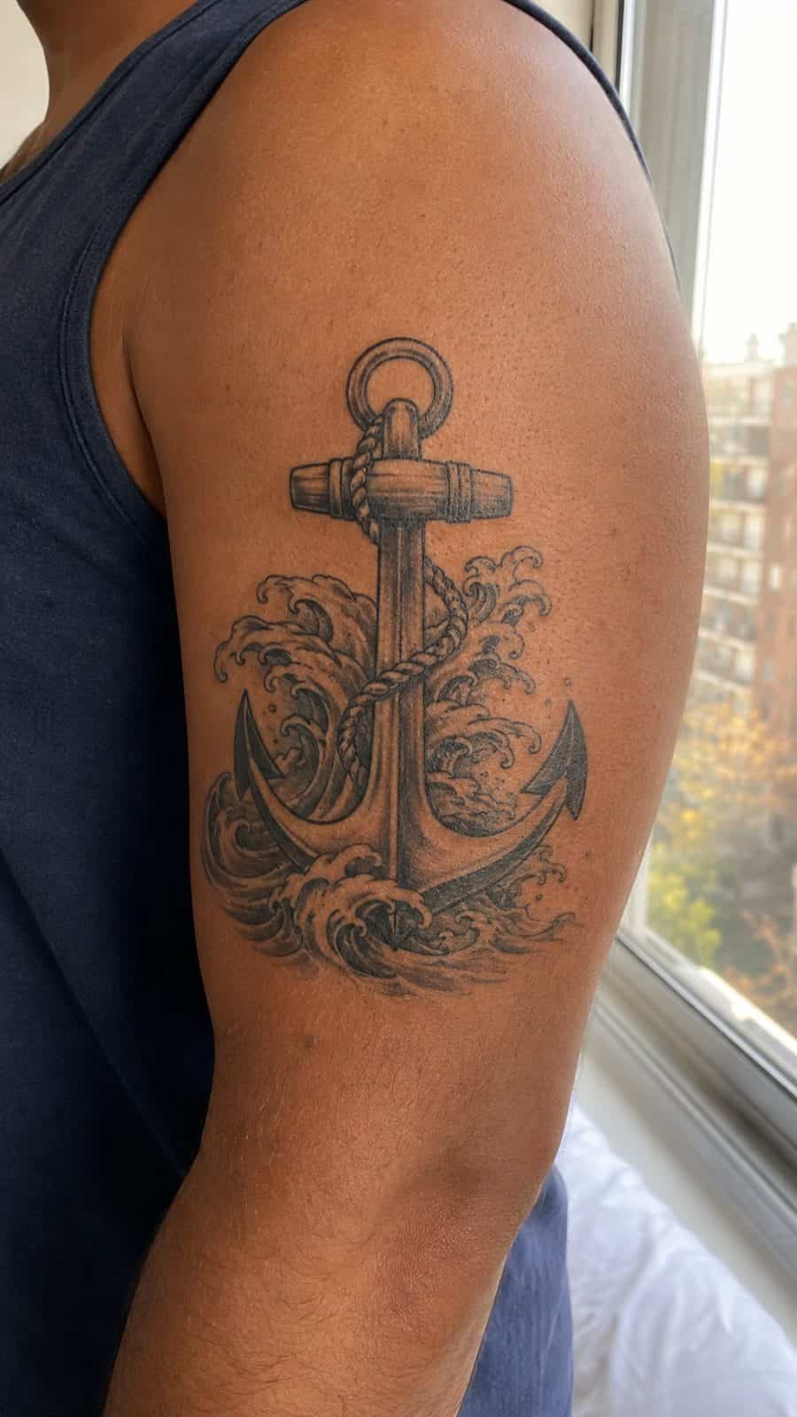 Healed anchor with waves tattoo on a adult person's outer upper arm, photographed in a natural slightly elevated close view — study 1