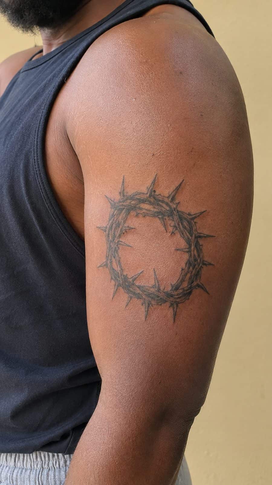 Healed crown of thorns tattoo on a adult person's outer upper arm, photographed in a natural straight-on close view, a touch — study 1