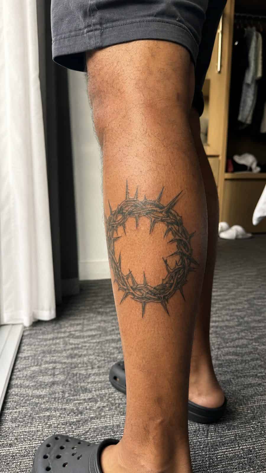 Healed crown of thorns tattoo on a adult person's outer calf, photographed in a natural gentle side angle that clearly shows how the — study 2