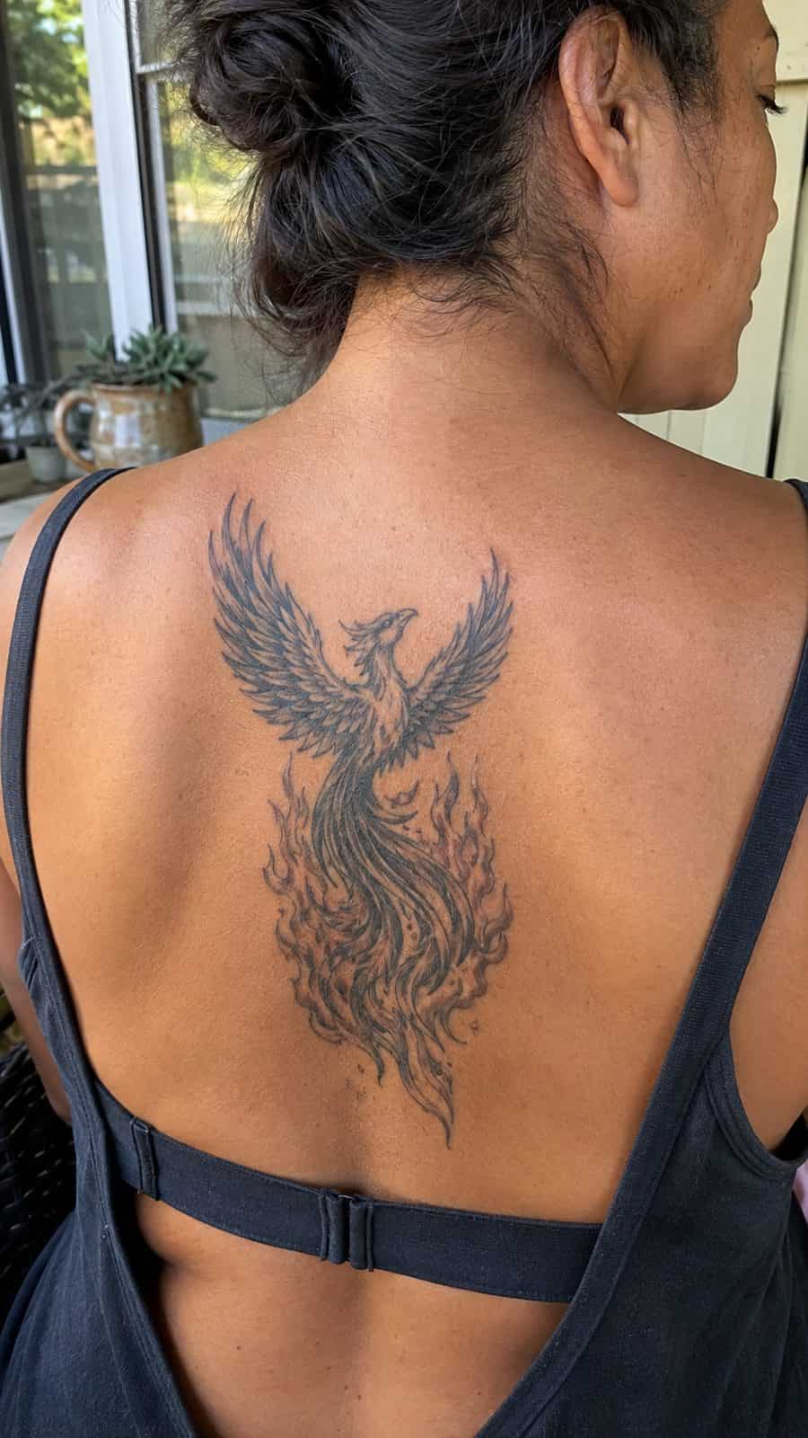 Healed phoenix rising tattoo on a adult person's upper back, photographed in a natural straight-on close view, a touch off-center like — study 1