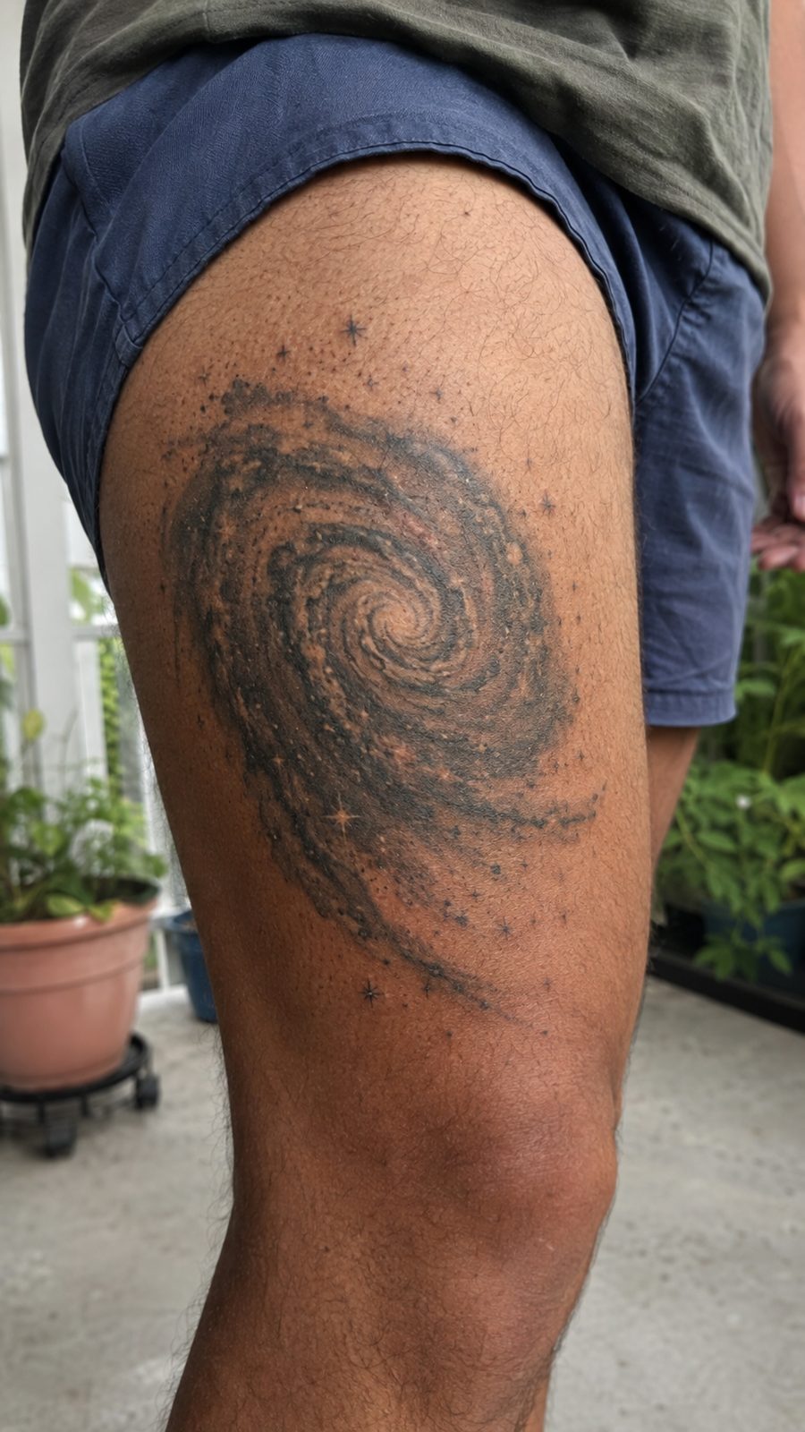 Healed spiral galaxy tattoo on a adult person's outer thigh, photographed in a natural straight-on close view, a touch off-center like — study 1
