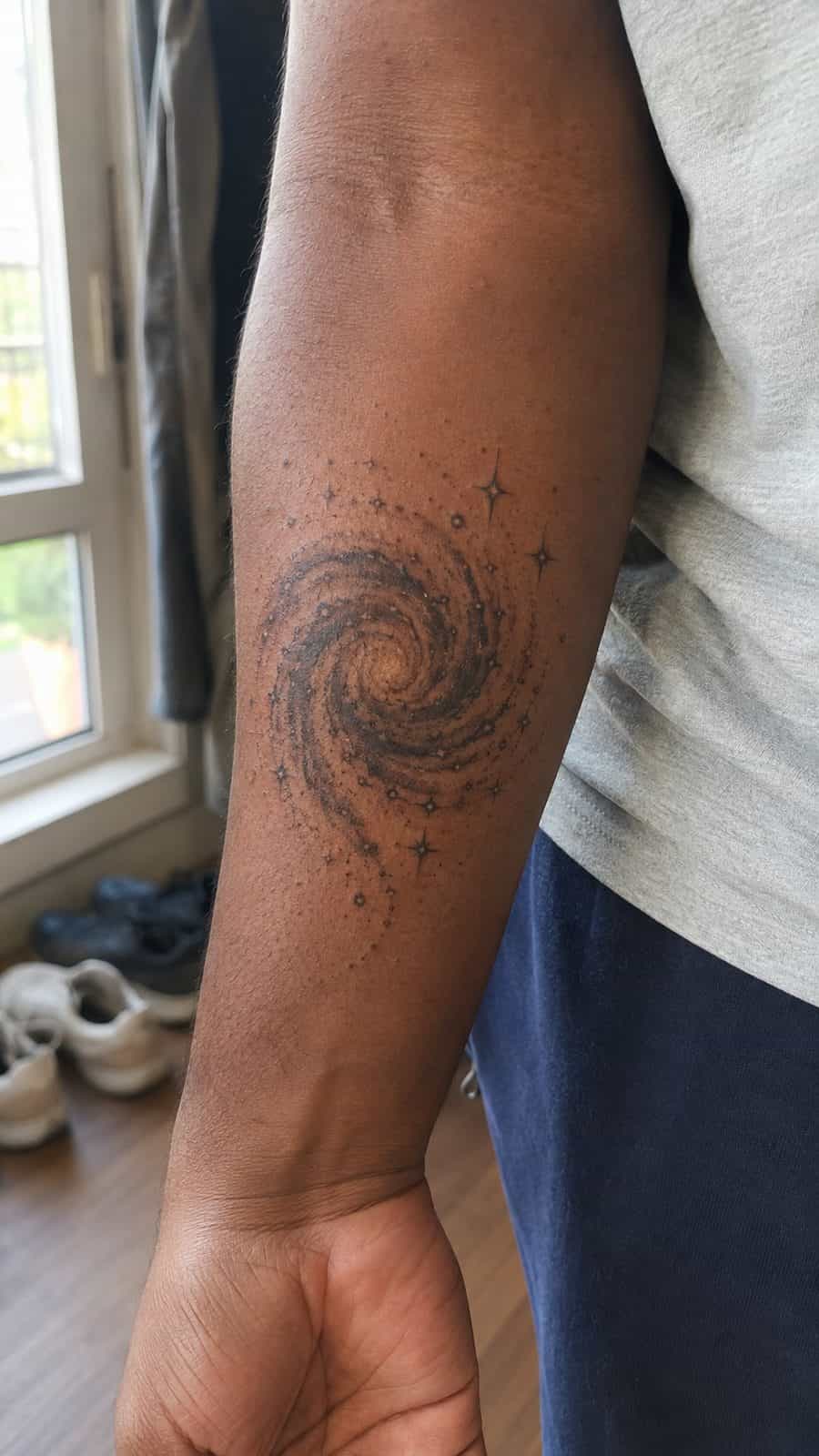 Healed spiral galaxy tattoo on a adult person's inner forearm, photographed in a natural slightly elevated close view — study 3