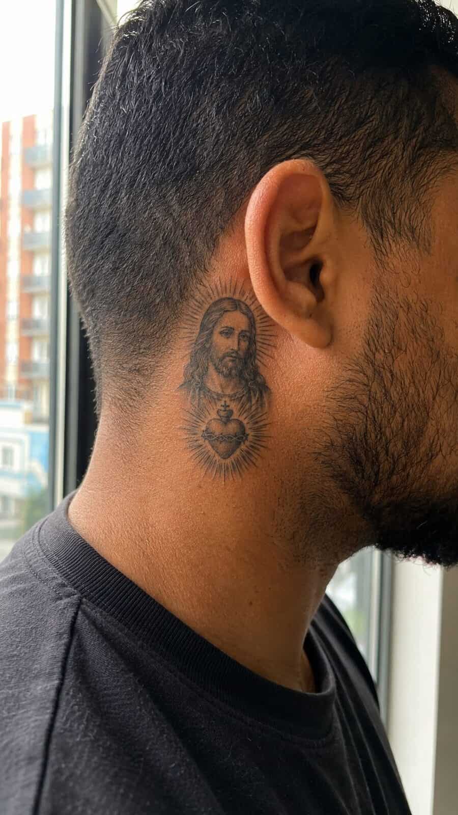 Exploring 18 Profound Jesus Tattoo Ideas for the Modern Man 3 Healed jesus and the sacred heart tattoo on a adult man's behind the ear, photographed in a natural gentle side angle that clearly — study 2