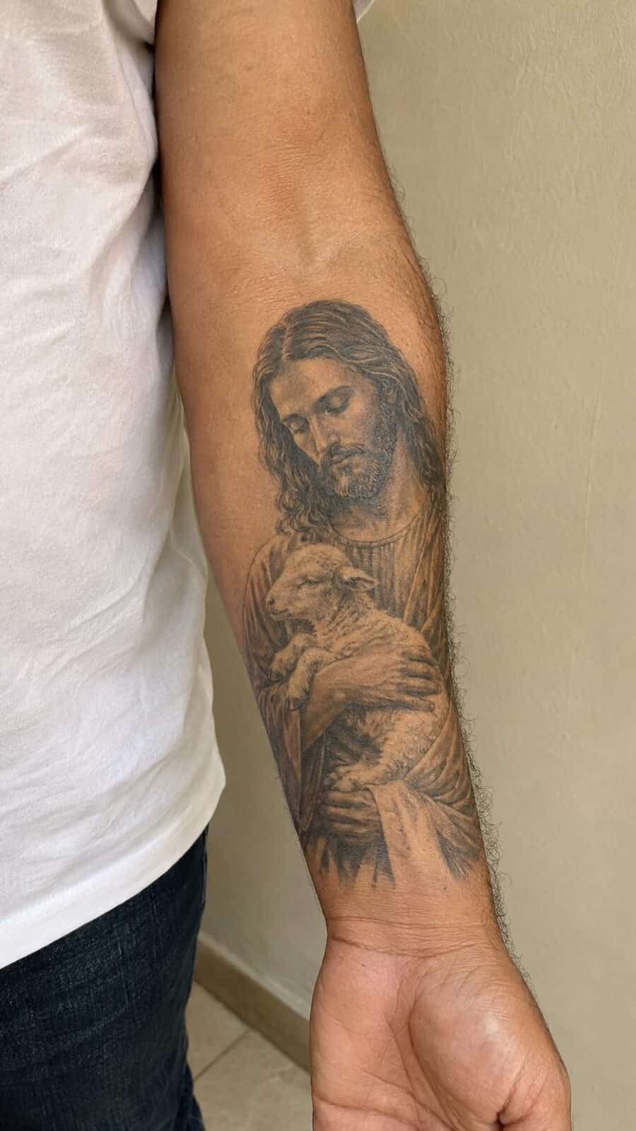 Exploring 18 Profound Jesus Tattoo Ideas for the Modern Man 10 Healed jesus with the lamb tattoo on a adult man's inner forearm, photographed in a natural slightly elevated close view — study 2