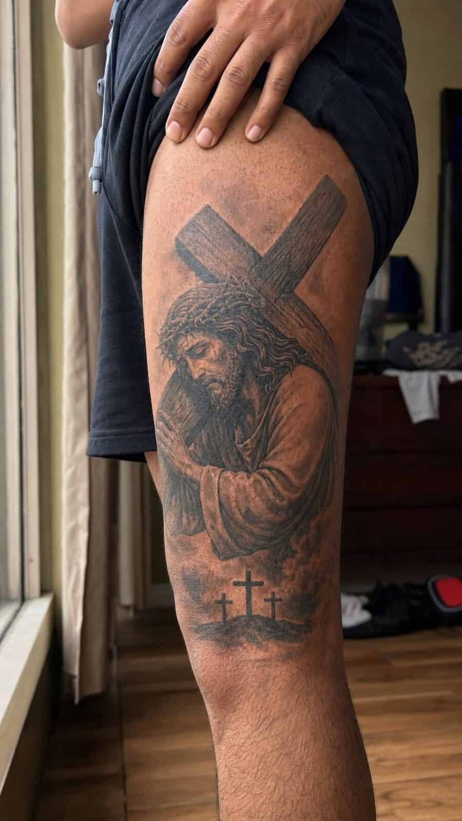 Exploring 18 Profound Jesus Tattoo Ideas for the Modern Man 13 Healed jesus with the cross tattoo on a adult man's outer thigh, photographed in a natural casual close three-quarter view — study 1