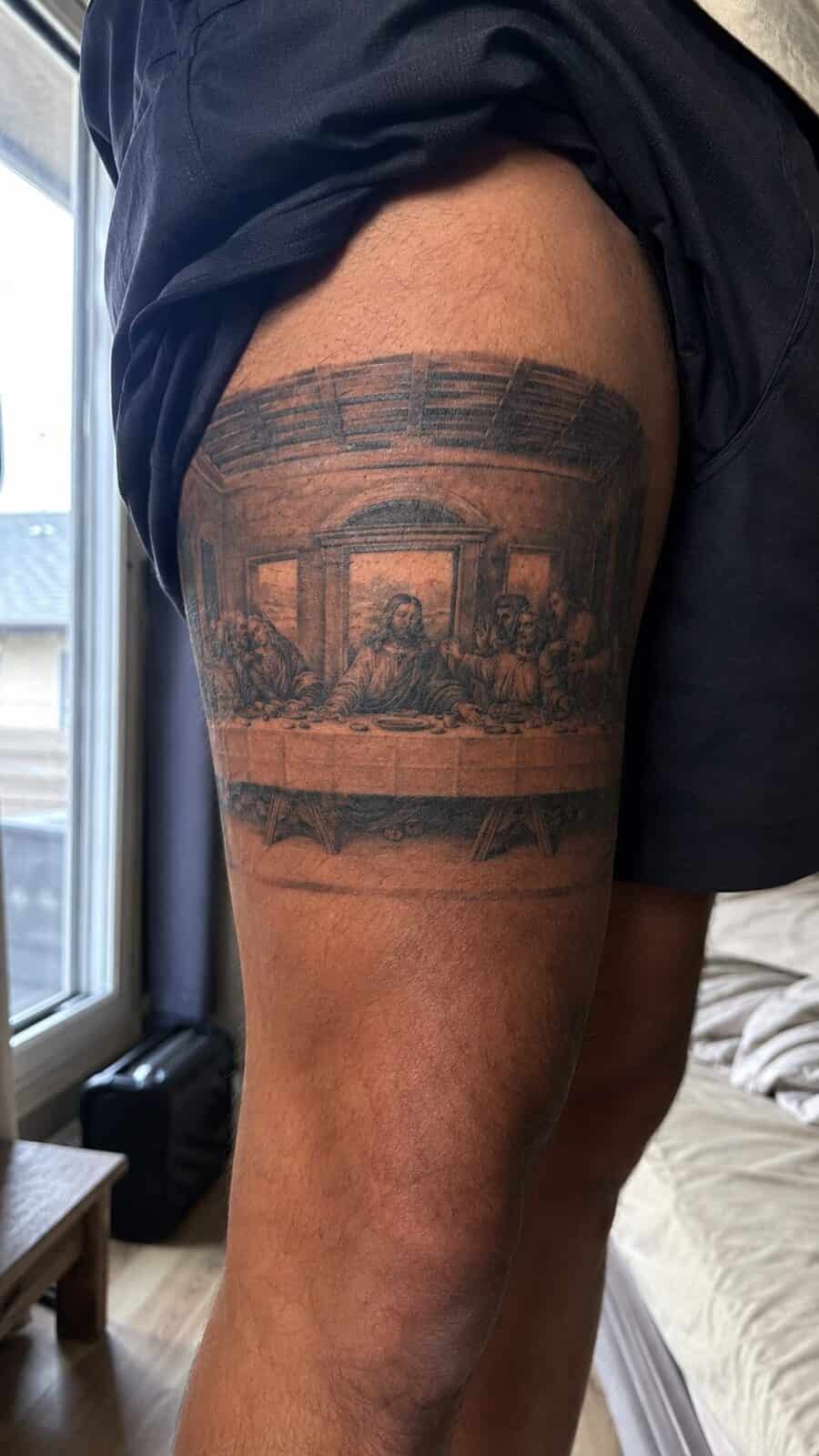 Exploring 18 Profound Jesus Tattoo Ideas for the Modern Man 18 Healed jesus and the last supper tattoo on a adult man's outer thigh, photographed in a natural casual close three-quarter view — study 1