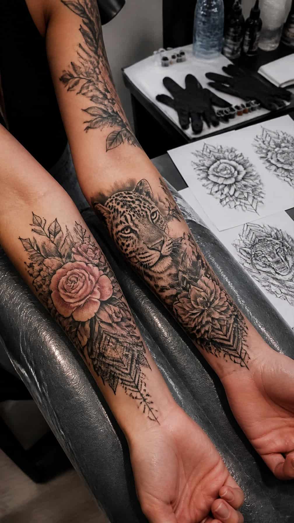 A tattoo artist’s studio workspace with a client’s arm displaying several finished cover-up tattoos.