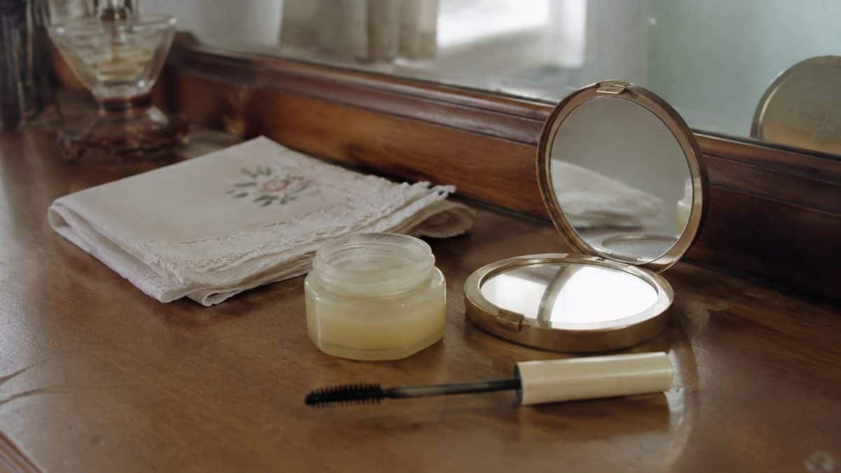 Vintage vanity with a jar of Vaseline and a mascara wand.