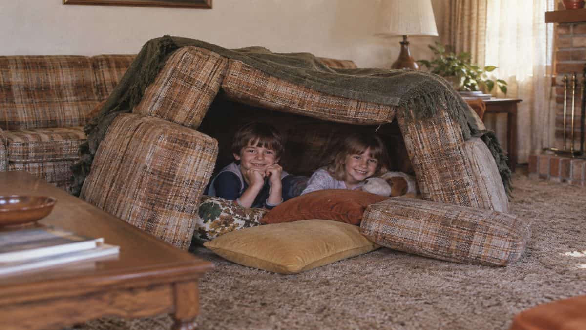 Before Screens: How We Entertained Ourselves 2 Children playing inside a messy couch cushion fort.