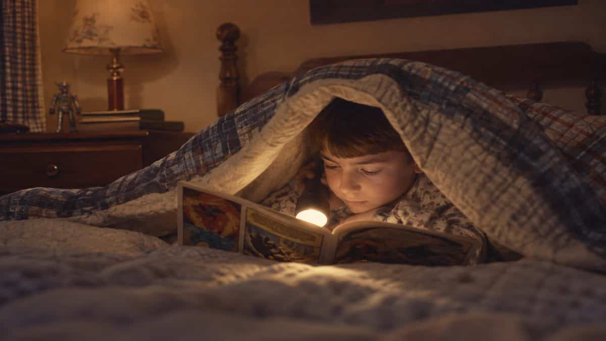 Before Screens: How We Entertained Ourselves 4 Child reading a recognizable comic book under covers.