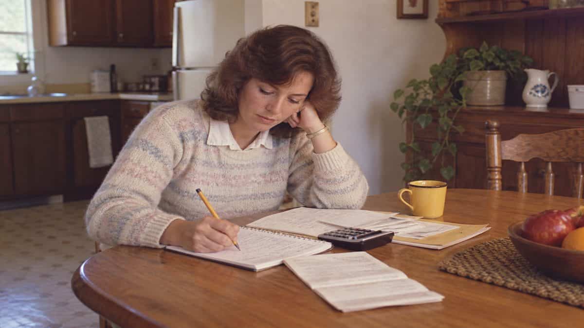 17 Life Skills We Learned Without the Internet That Made Us Smarter 16 Someone calculating a budget with paper and pencil