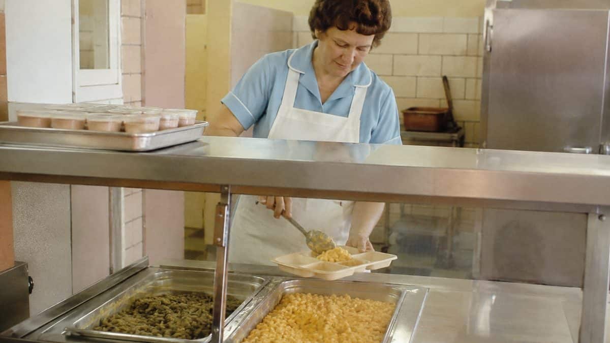 School Cafeteria Food from the '70s We Secretly Loved 15 Cafeteria worker serving mac and cheese.