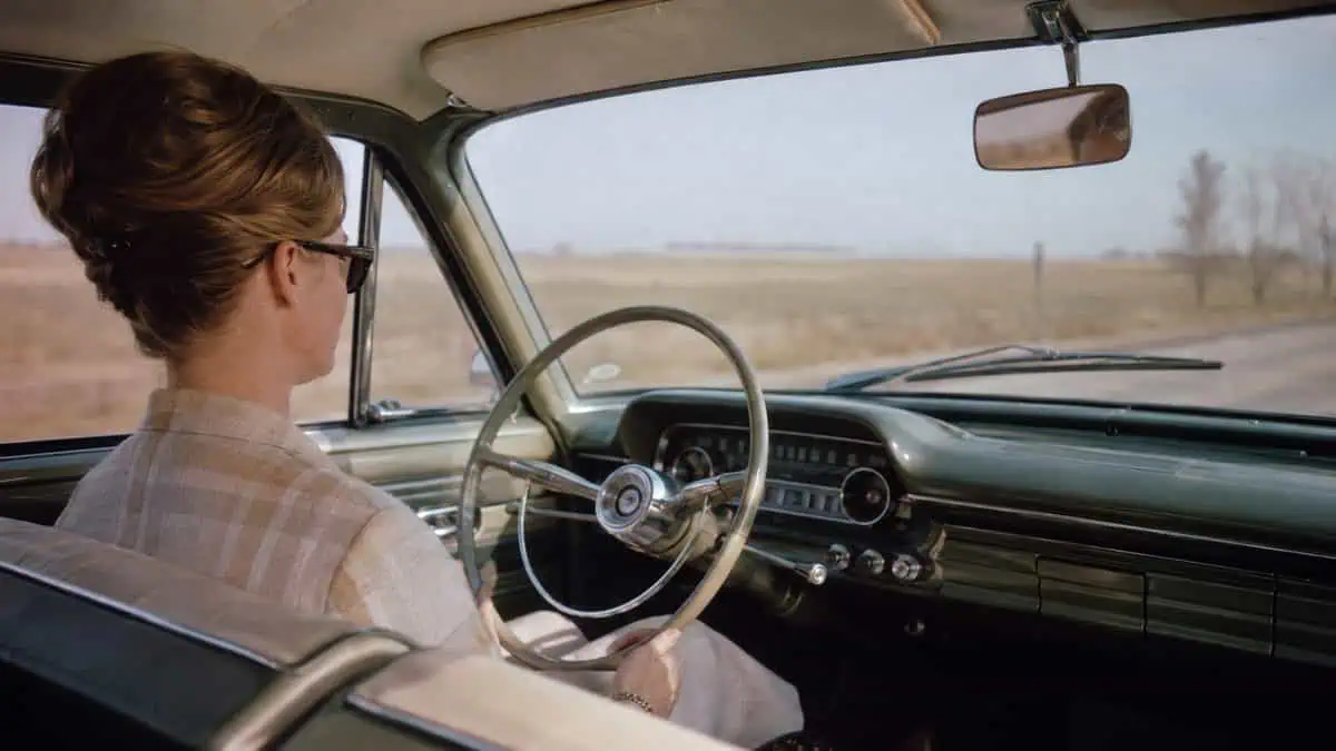 Someone driving a 1960s car