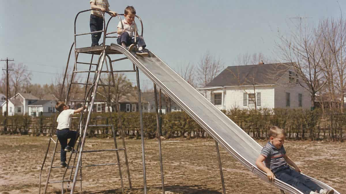 Parenting Practices from the '60s That Were Completely Normal Then 6 Children playing on a metal jungle gym or tall slide