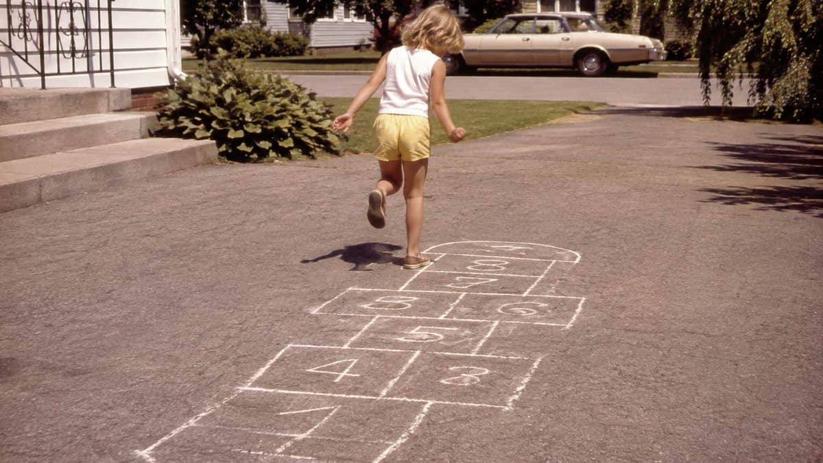 Backyard Games from the '70s That Kept Kids Outside Until Dark 11 Real 1970s photo of kids playing hopscotch with clear chalk numbers