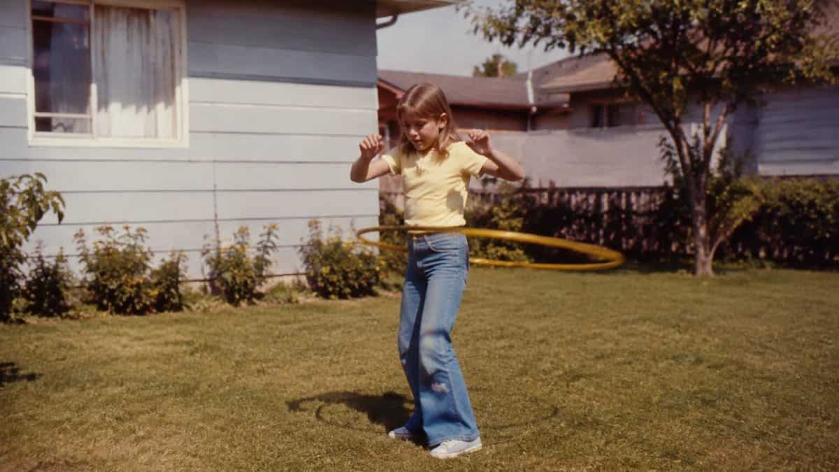 Backyard Games from the '70s That Kept Kids Outside Until Dark 6 Authentic 1970s photo of a child hula hooping.