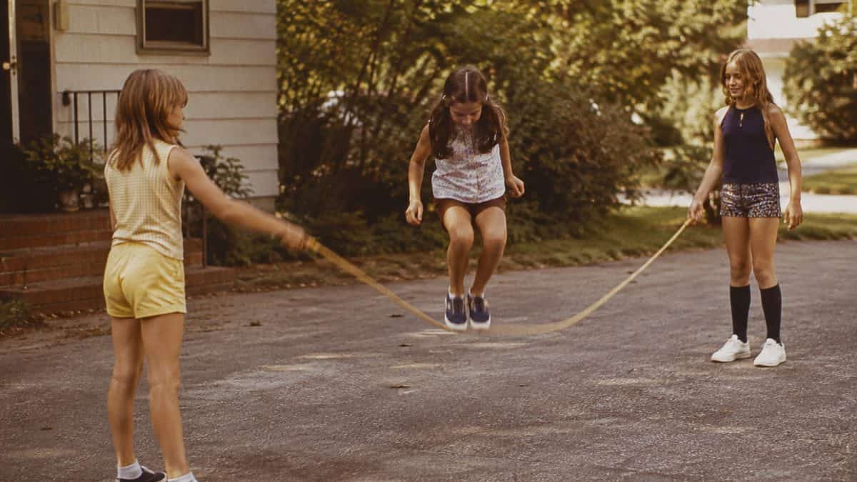 Backyard Games from the '70s That Kept Kids Outside Until Dark 8 Children playing Chinese jump rope.