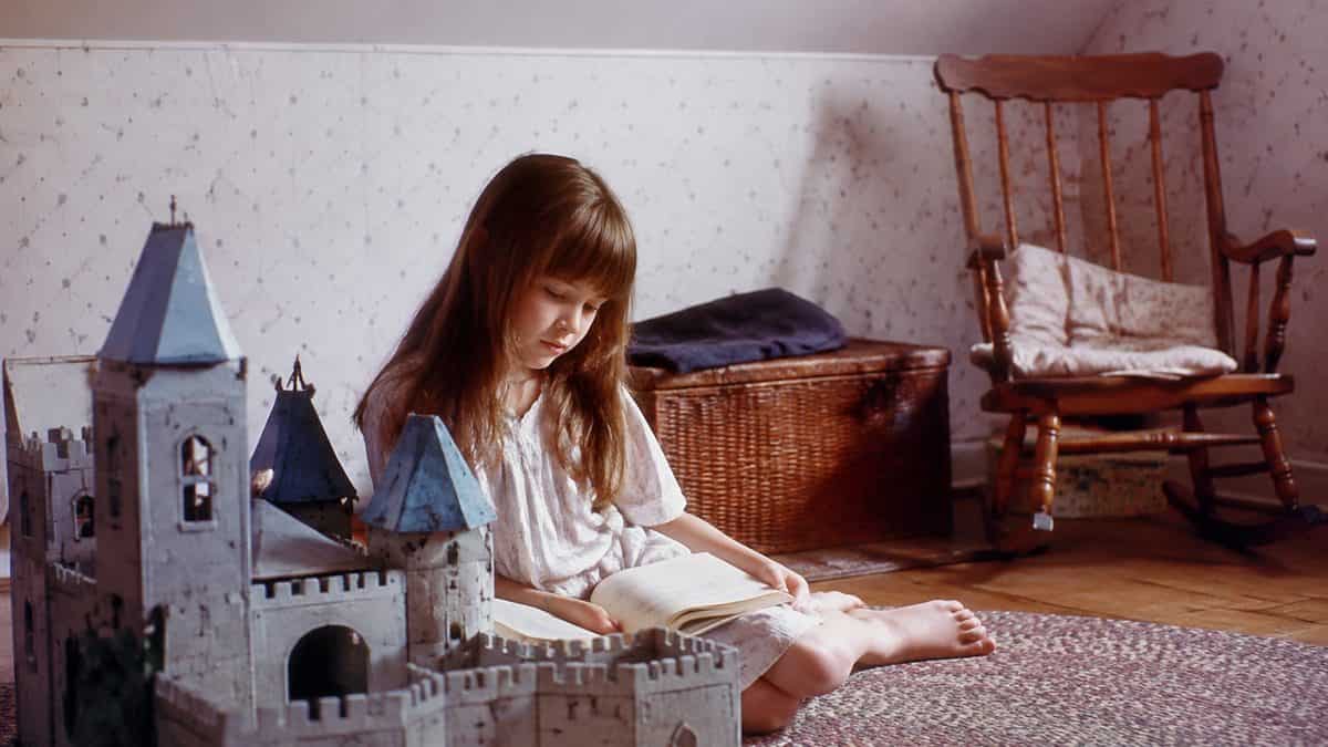 Authentic 1980s photo of a child playing with a toy castle or reading.