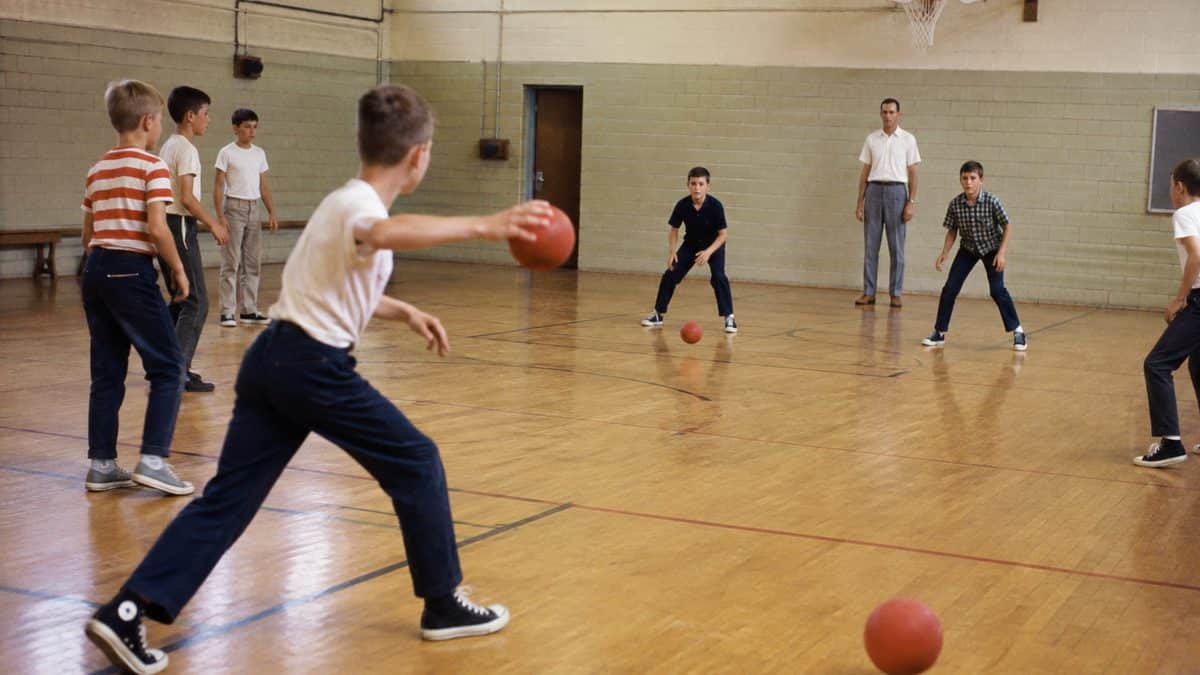 Kids playing dodgeball in a 1960s gym
