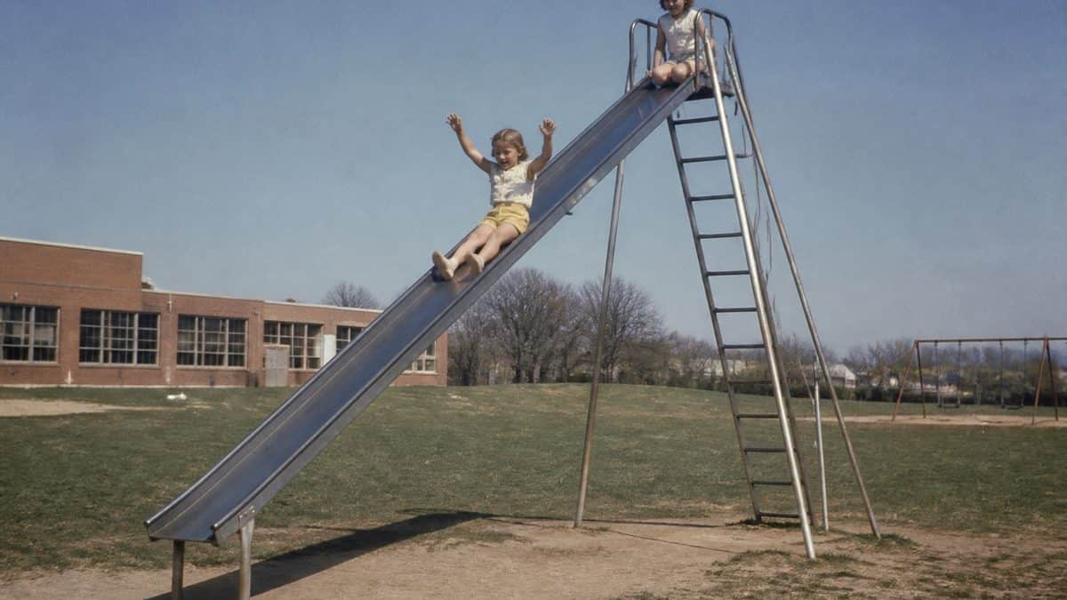 Children playing on a tall metal playground slide.