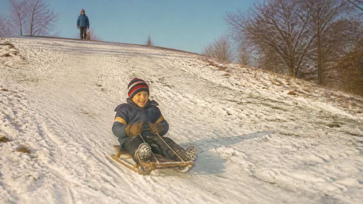Child on a sled on a snowy hill.