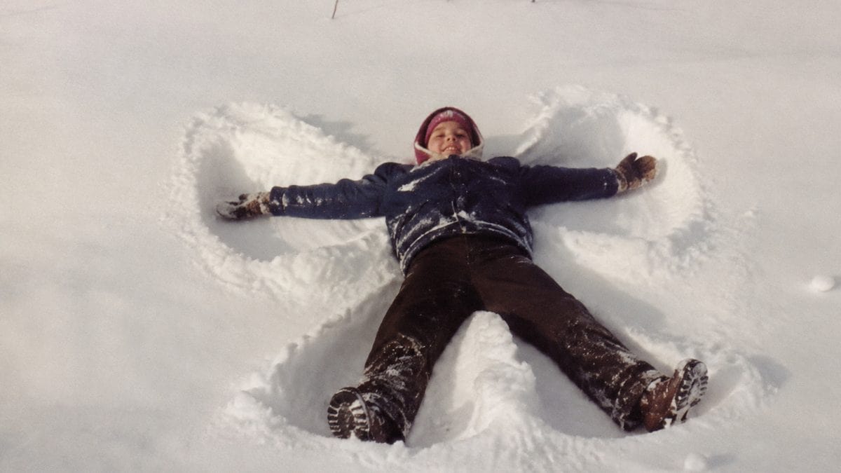 Child making a snow angel with natural snow displacement.