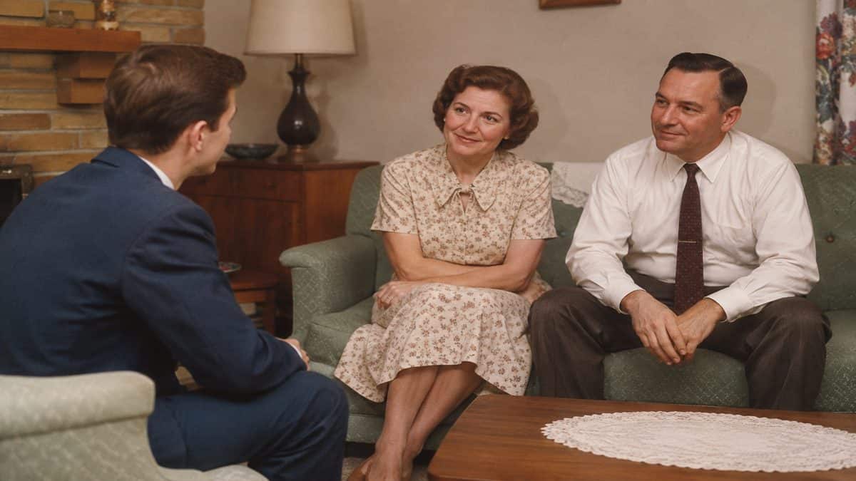 Young man meeting parents in a 1950s living room.