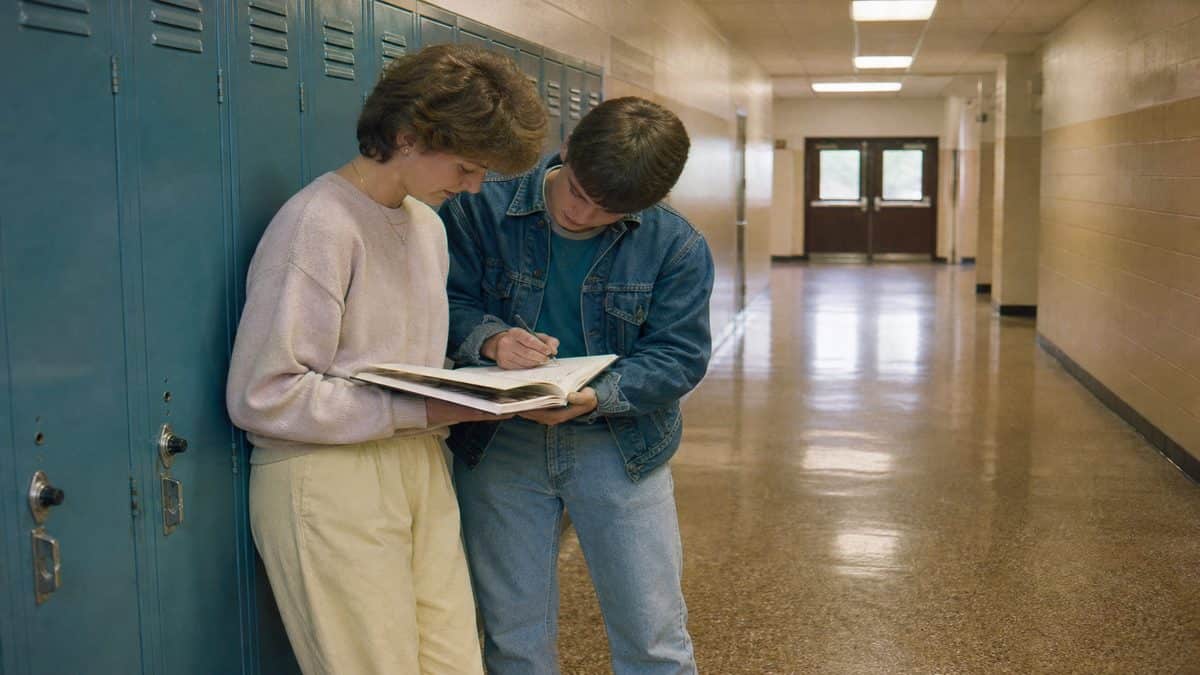 Students signing yearbooks in a school hallway.