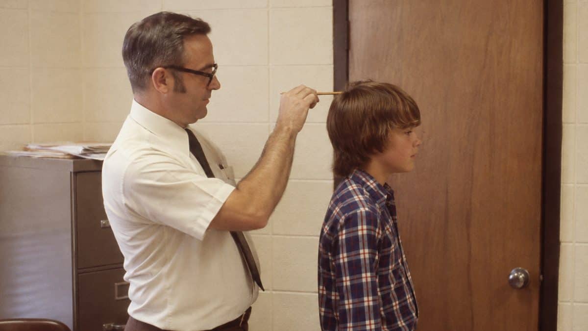 Authentic 1970s photo of a teacher checking a student's hair length