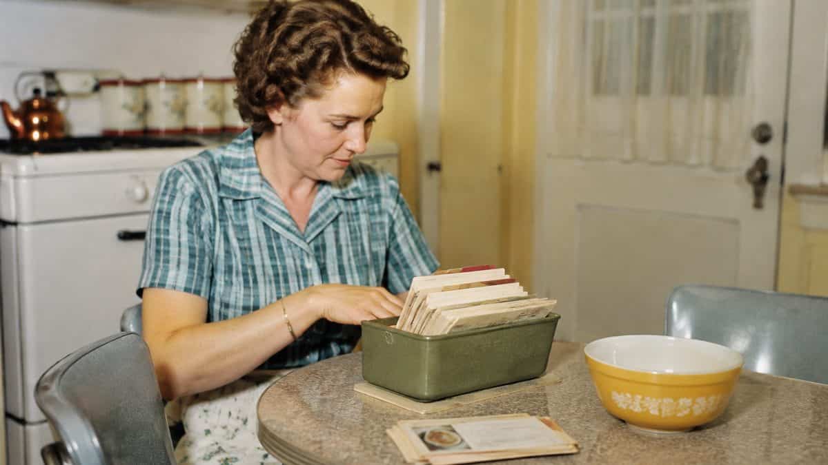 How '50s Moms Kept the Family Organized Without Any Tech 3 Genuine mid-century photo of a woman organizing real recipe cards