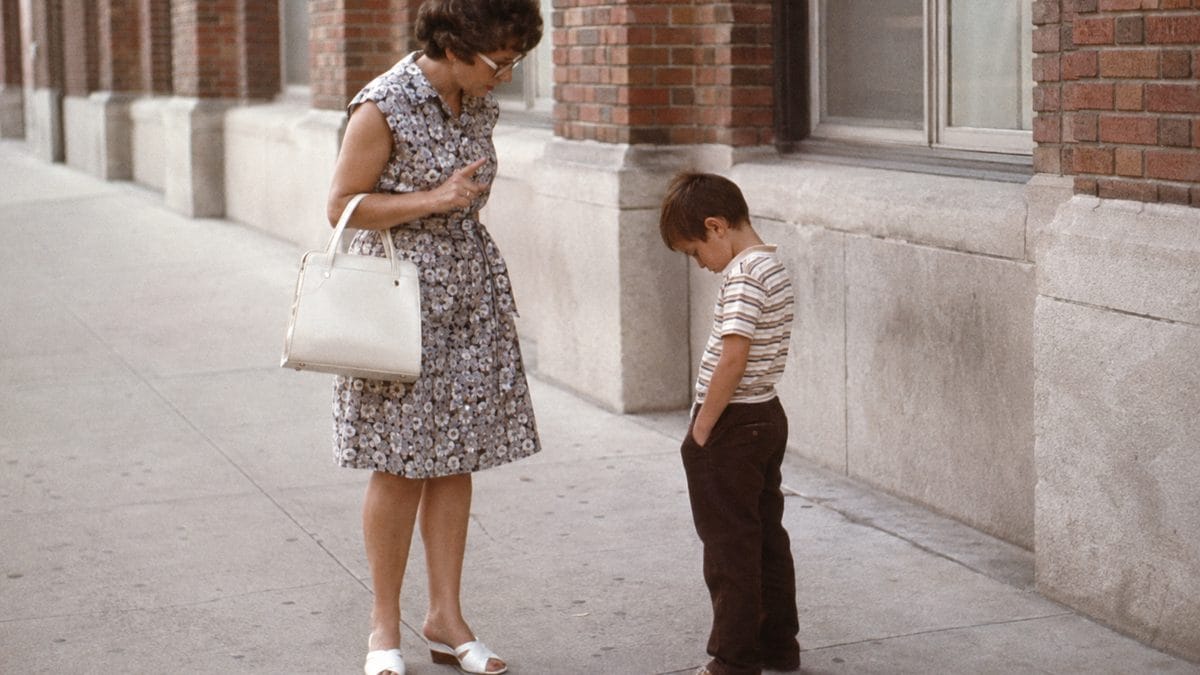 Parenting Practices from the Past That Would Be Illegal Today 5 Parent scolding a child in public with a neutral expression.