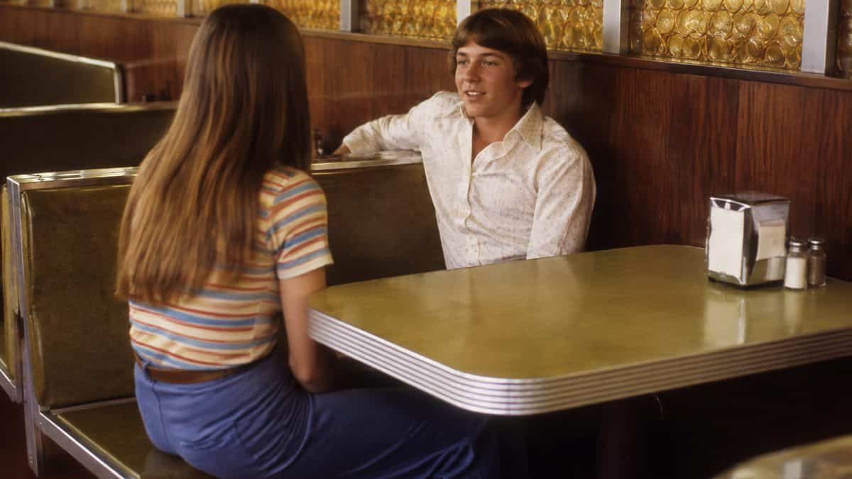 Dating Rules from the '70s That Sound Completely Insane Now 16 Real 1970s photo of teens at a diner or burger joint.