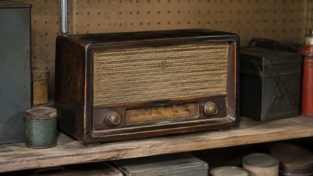 Real photo of a vintage radio sitting on a shelf or workbench in a garage.