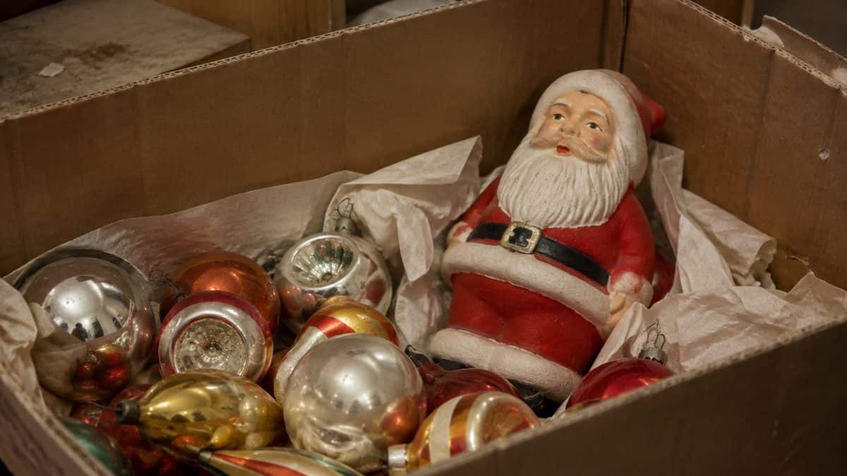 Real photo of vintage glass ornaments and a retro Santa figurine in a storage box.