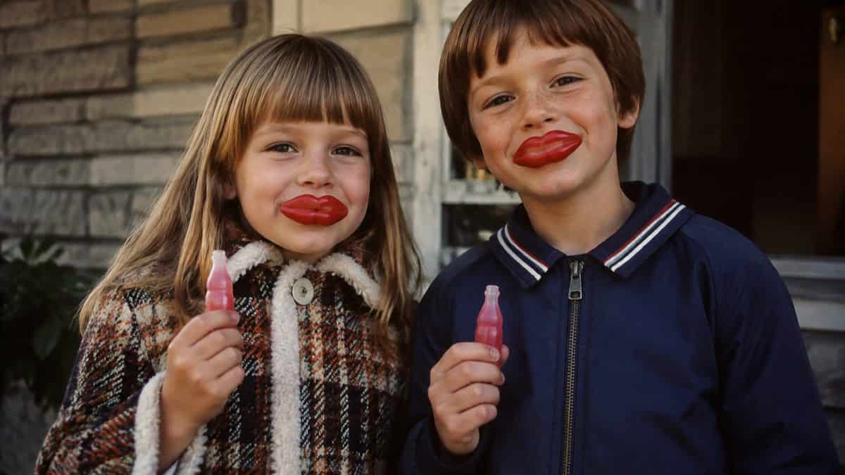 14 Things That Made Halloween Better in the '70s 12 Vintage-style photo of kids smiling while wearing wax lips and holding wax bottles