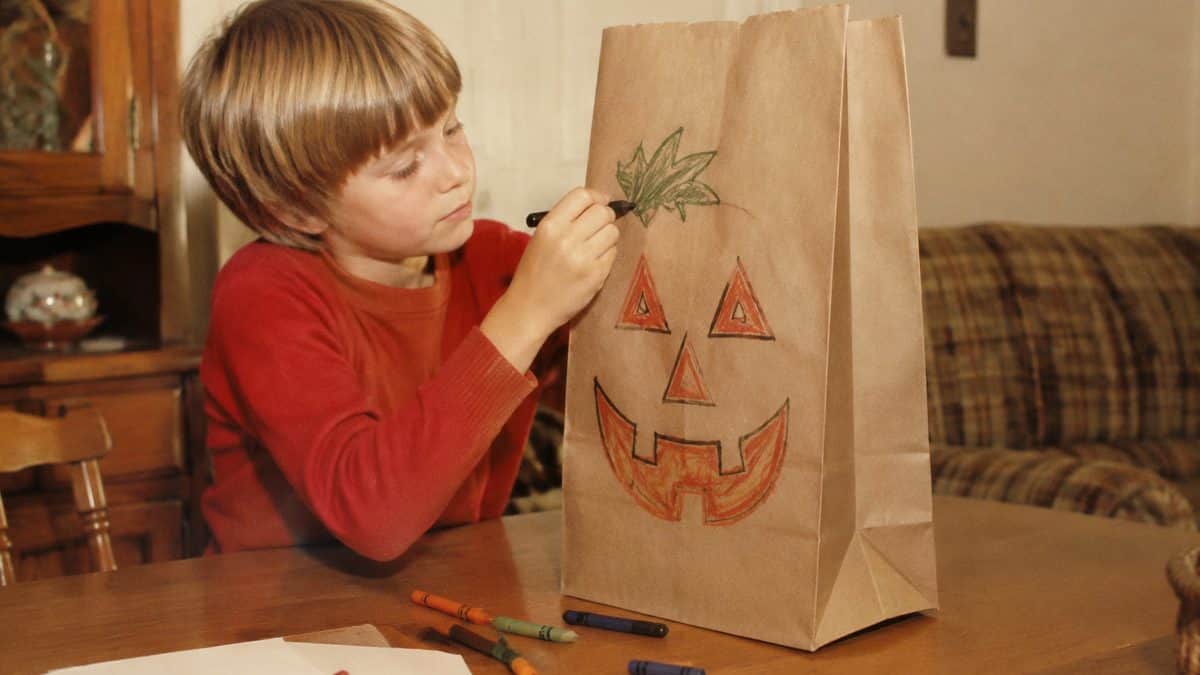 14 Things That Made Halloween Better in the '70s 13 Genuine vintage photo of a child decorating a brown paper grocery bag for trick-or-treating