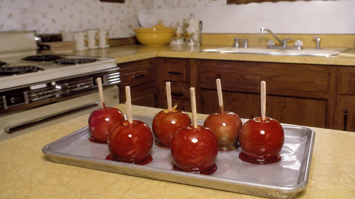 14 Things That Made Halloween Better in the '70s 15 Realistic photo of homemade candy apples cooling on a tray in a retro kitchen