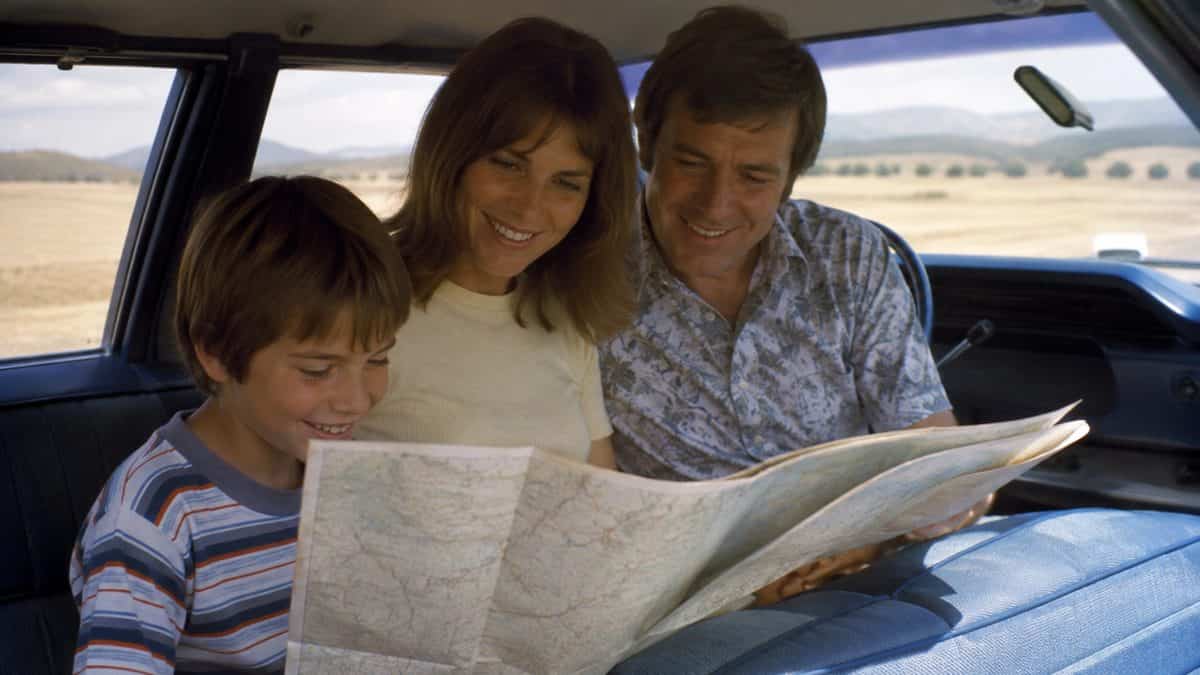 Smiling family looking at map in car.