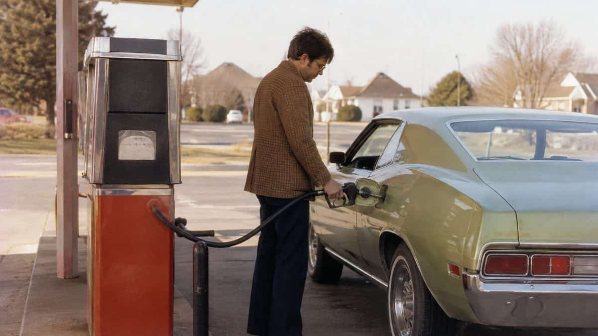 Real vintage photo of a 1970s gas station or someone pumping gas.