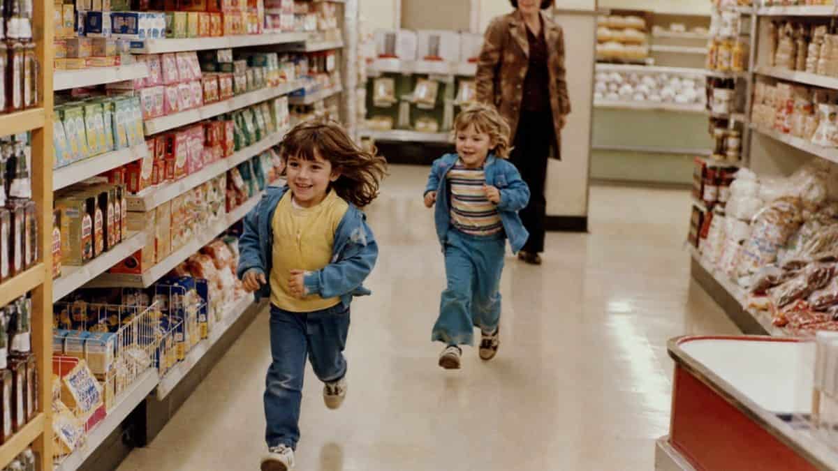 What Kids Used to Do at the Grocery Store That's Unthinkable Now 3 Children running past grocery aisles featuring natural faces, anatomically correct limbs, and no garbled packaging text