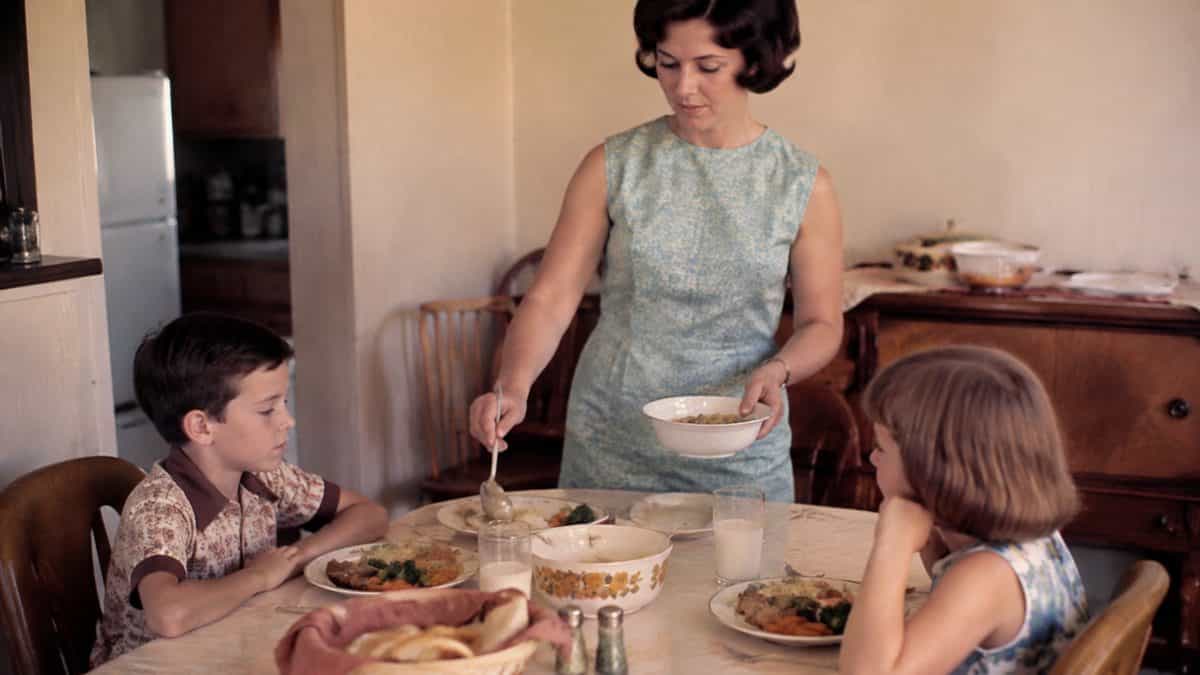Mother serving a meal to her children with neutral expressions